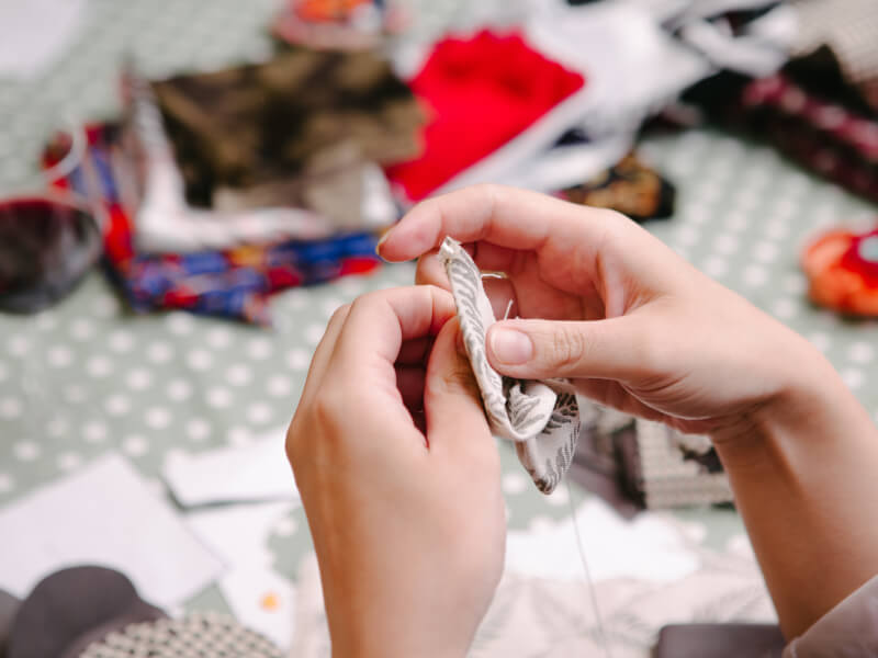 Hands sewing fabric in a sewing class